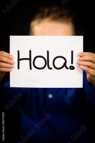 Child holding sign with Spanish word Hola - Hello