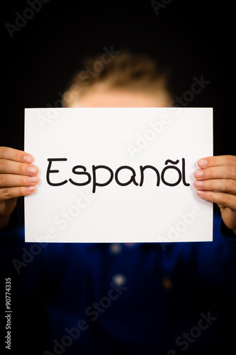 Child holding sign with Spanish word Espanol - Spanish in Englis