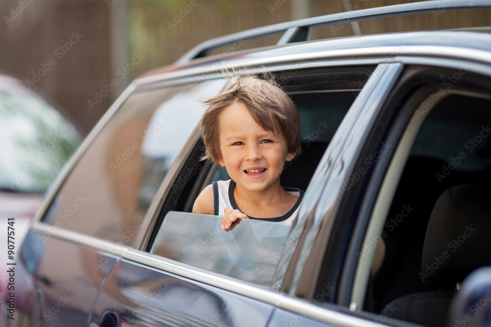 Little cute child, boy, looking out the window of a car