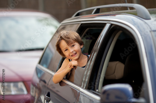 Little cute child, boy, looking out the window of a car