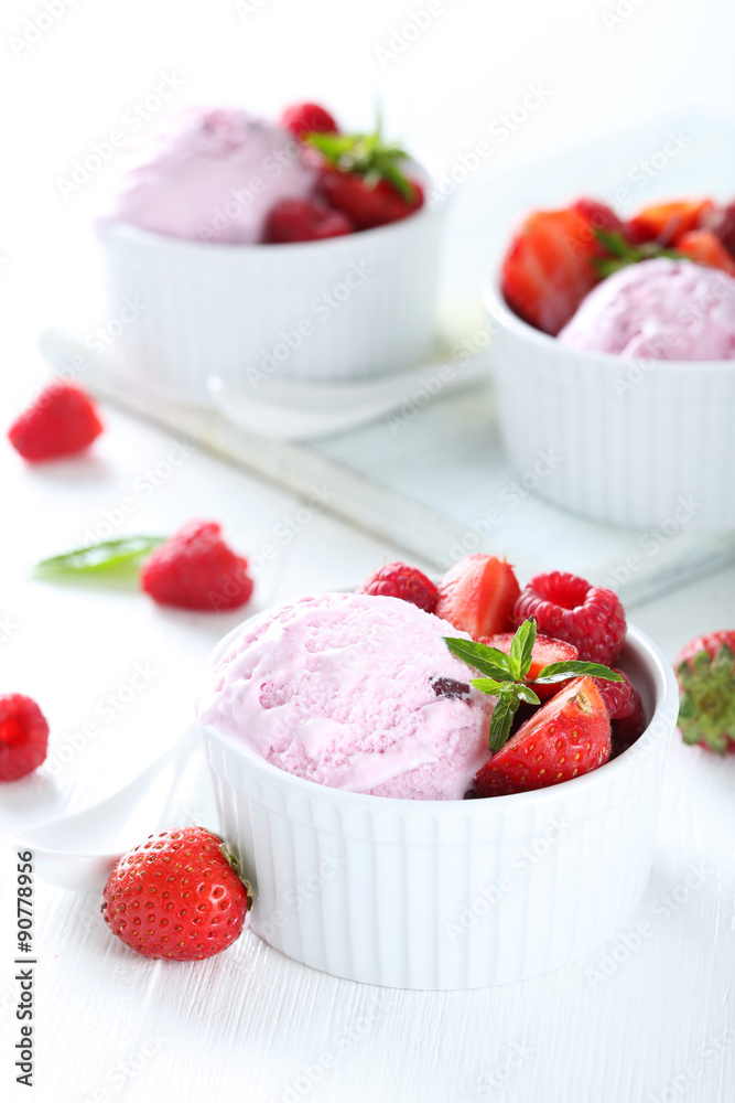 Ice cream in bowl with strawberries and raspberries on white woo Ice cream in bowl with strawberries and raspberries on white woo