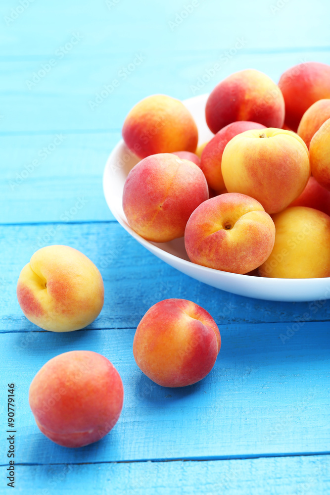 Fresh apricots in plate on a blue wooden background Fresh apricots in plate on a blue wooden background