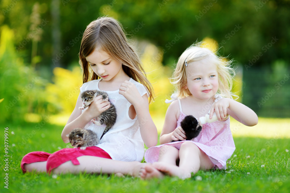 Two little sisters feeding kittens with milk Two little sisters feeding kittens with milk