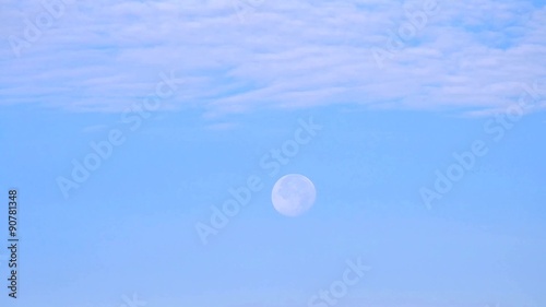 Moon moves across blue sky with beautiful cirrus clouds photo