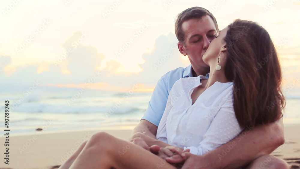 Attractive Young Brunette couple holding each other. romantic in love kissing at beach sunset. Newlywed happy young couple enjoying ocean sunset during travel holidays vacation getaway. 