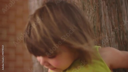 A little girl standing in a tree and smiling for a photo, then getting down