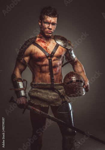 Muscular bloody gladiator with sword and helmet.