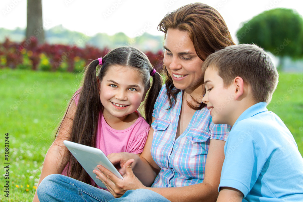 Happy Family using laptop lying on grass Happy Family using laptop lying on grass