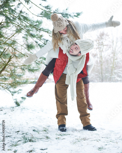 Mann trägt Frau huckepack durch Schnee