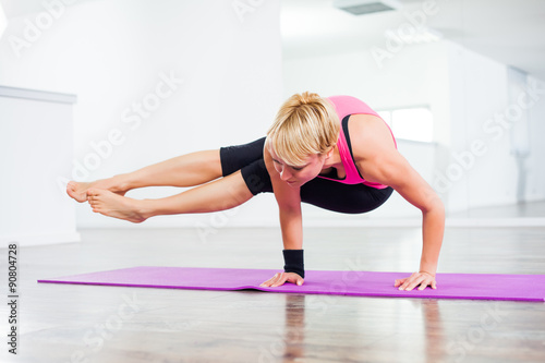 Young woman practicing yoga, Astavakrasana / Eight Angle Pose