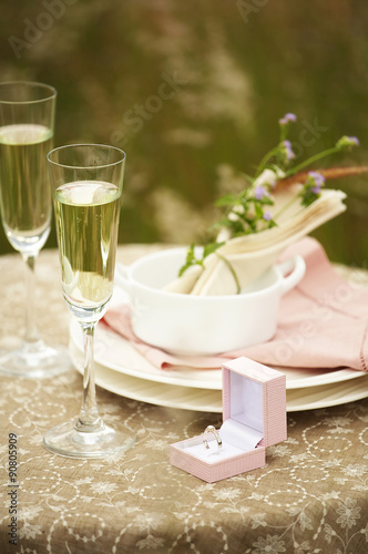 white wine in glass and diamond ring on table