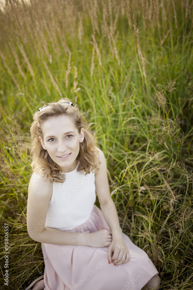 Happy woman relaxing on meadow. Sitting with happy expression on her face. Beautiful summer day on field. Happy woman relaxing on meadow. Sitting with happy expression on her face. Beautiful summer day on field.