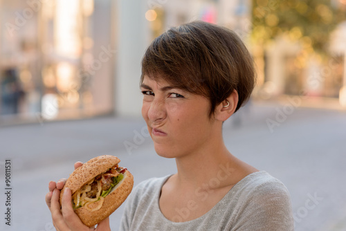 Young woman grimacing in distaste at a burger