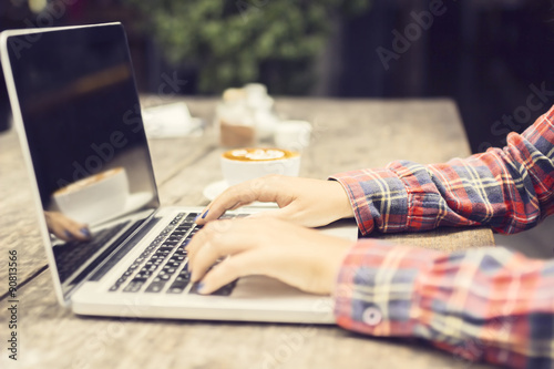 Girl hands with laptop and cup of coffee on a wooden table