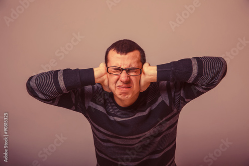 European-looking man of 30 years with glasses, his hands coverin photo