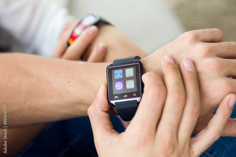 Beautiful young couple using a smartwatch at home. Beautiful young couple using a smartwatch at home.