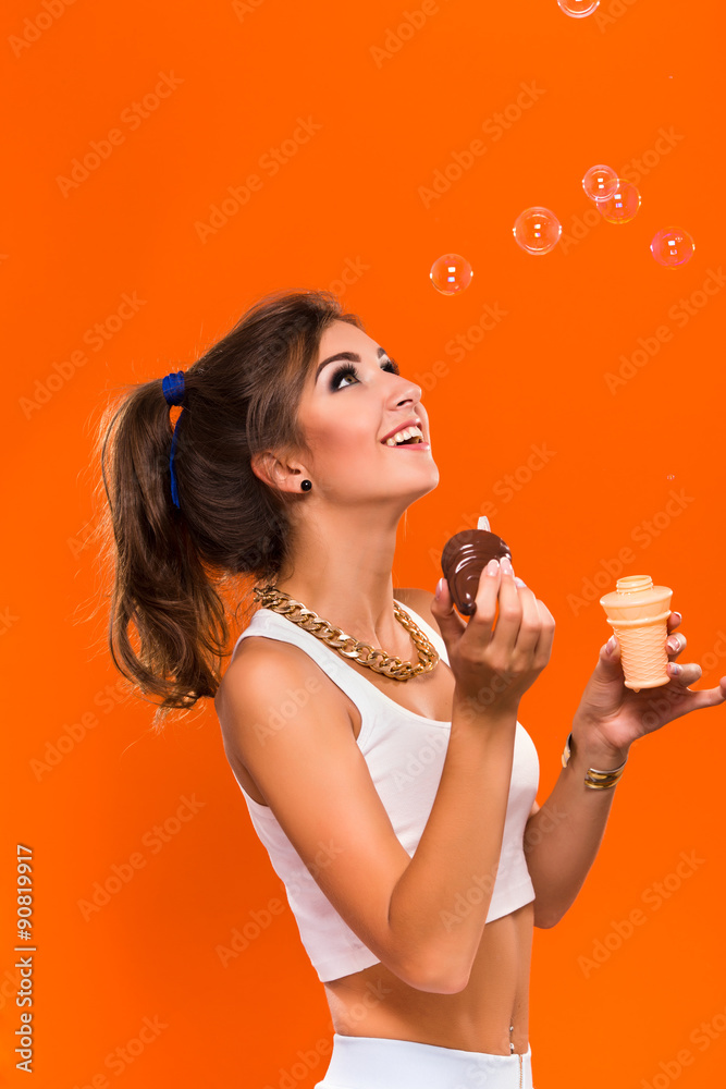 Pretty happy girl posing with bubbles on the orange background Pretty happy girl posing with bubbles on the orange background