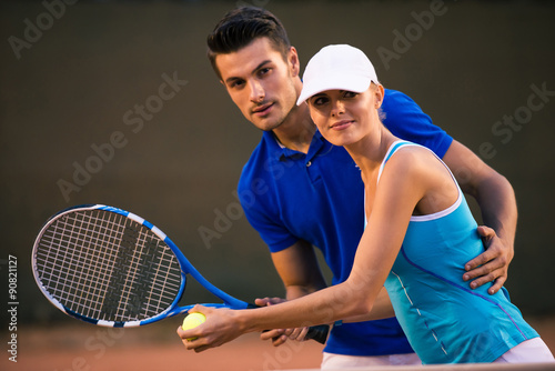 Man training her girlfriend how to play tennis