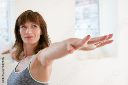 Woman doing Virabhadrasana yoga pose in gym