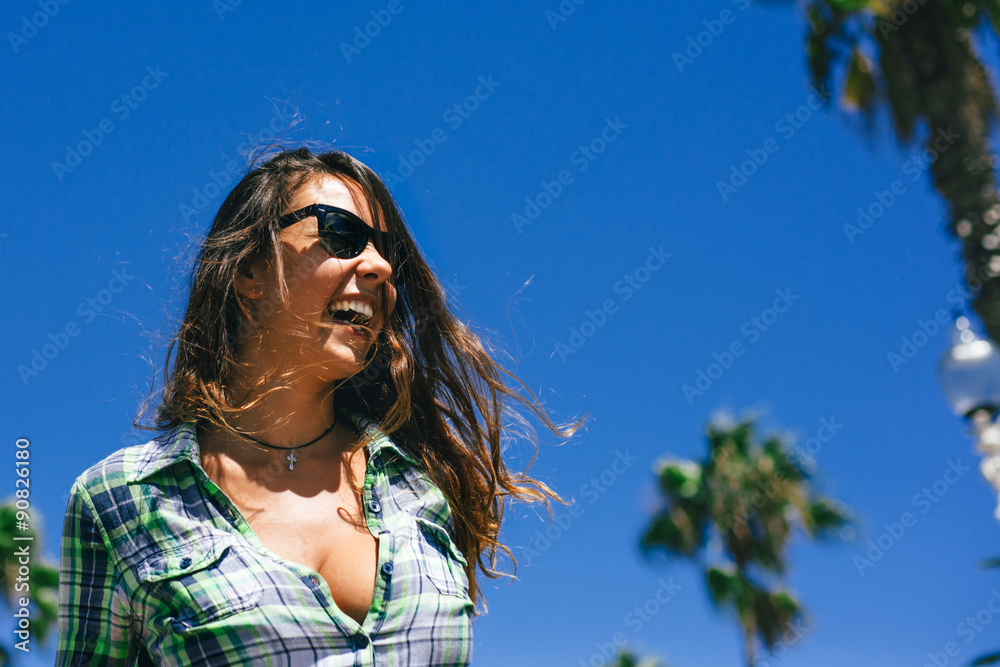 portrait of beautiful young girl in sunglasses in palm trees in summer in sunglasses smiling wide in Barcelona portrait of beautiful young girl in sunglasses in palm trees in summer in sunglasses smiling wide in Barcelona