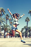 Beautiful young crazy happy girl is jumping in palm trees in summer in Barcelona wearing sunglasses blue jeans shirts