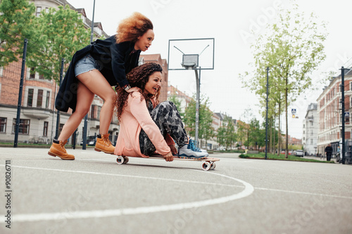 Young women having fun together with skateboard