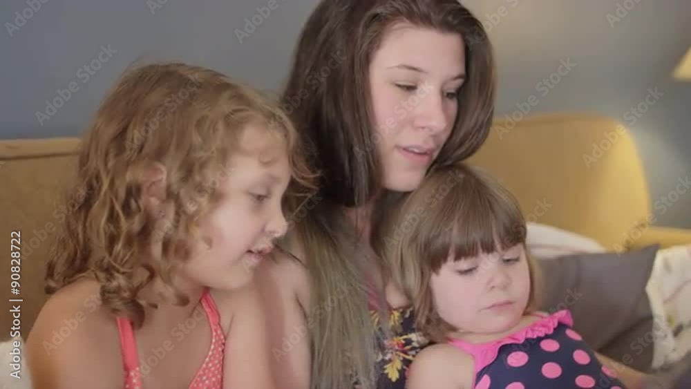 A mother reads a book to her daughters on the couch
A mother reads a book to her daughters on the couch