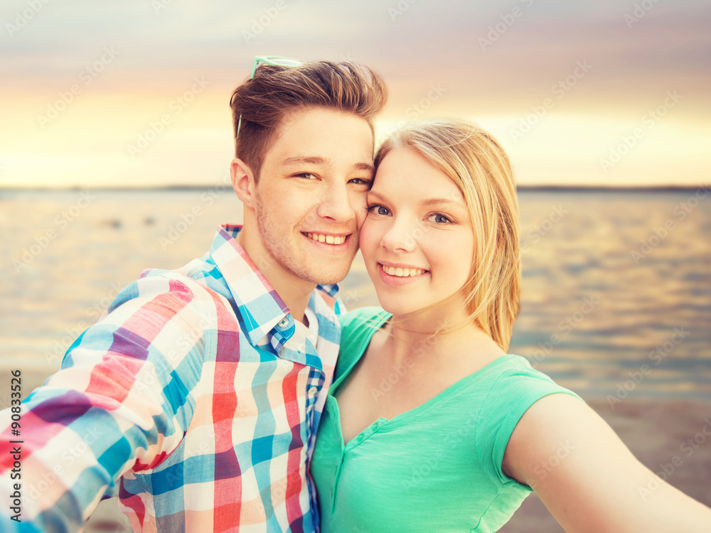 smiling couple with smartphone on summer beach