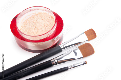 Three professional make-up brushes and powder on white
