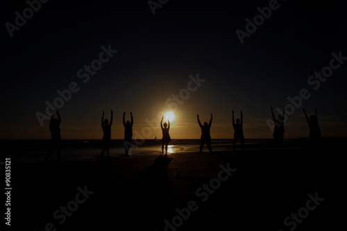 yoga in group in back light of the sunset