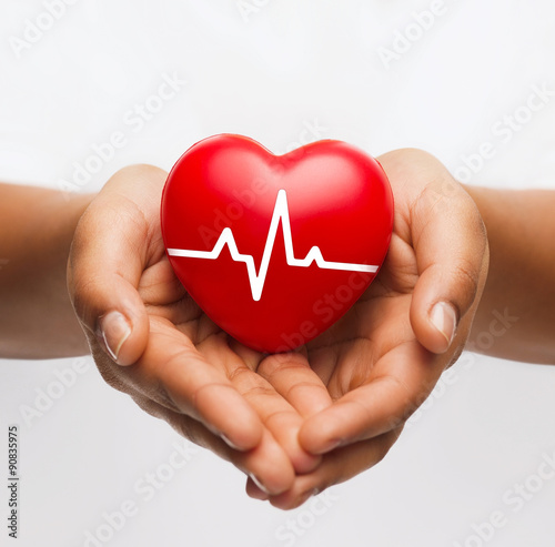 female hands holding heart with ecg line