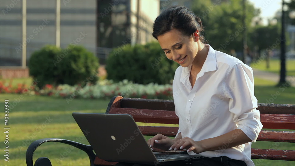 Cheerful girl with laptop on the bench Cheerful girl with laptop on the bench