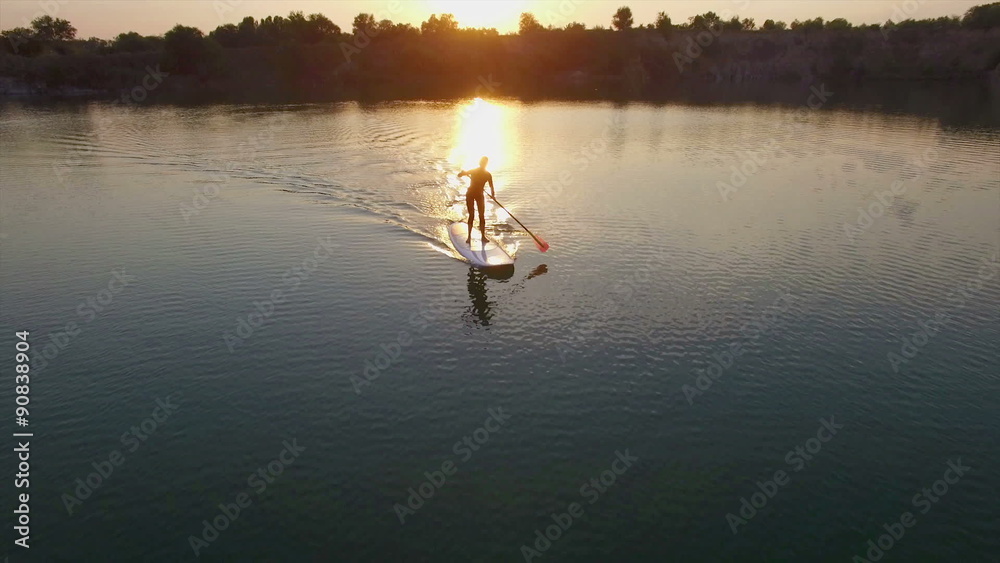 Aerial: young girl boarding SUP