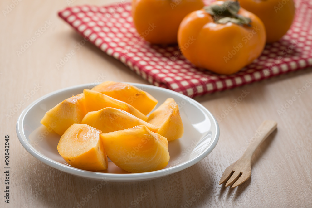 Cut fruit, fresh persimmon on dish.