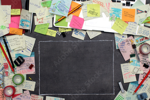 Office desk covered by post it papers and chalkboard frame