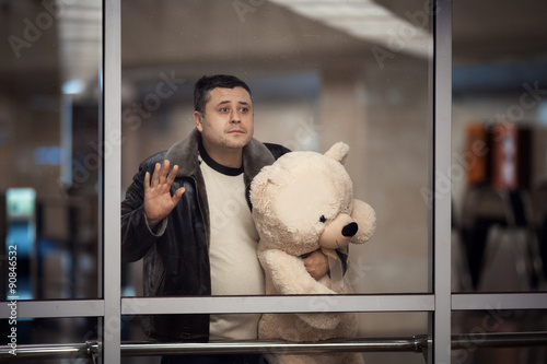 Man holding toy bear and looking sadly into the distance. photo