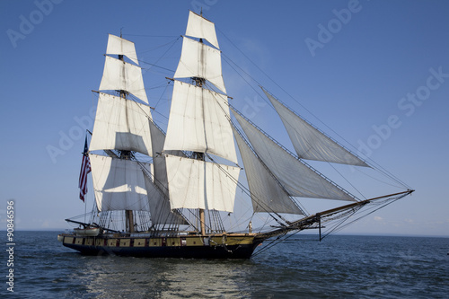 Tall ship with American flag sailing on blue waters