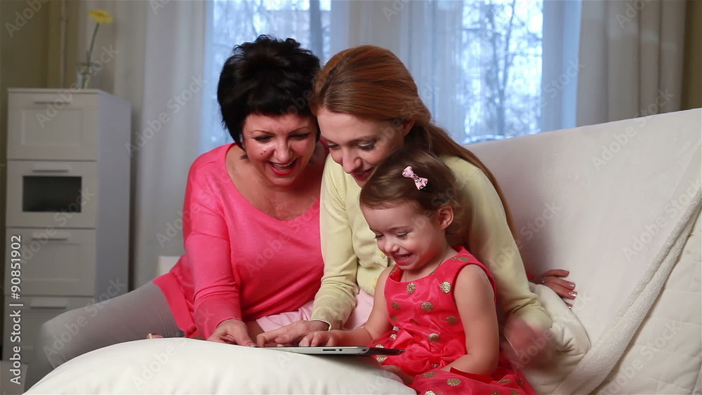 Three generations of women in one family. Little girl and her mother and grandmother use touch screen tablet. Three generations of women in one family. Little girl and her mother and grandmother use touch screen tablet.