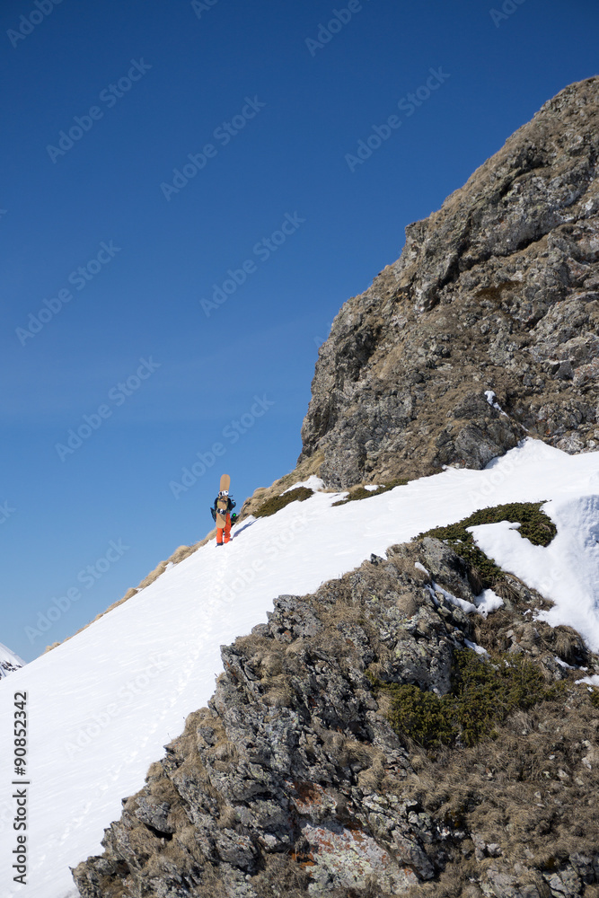 Snowboarder walking uphill for freeride