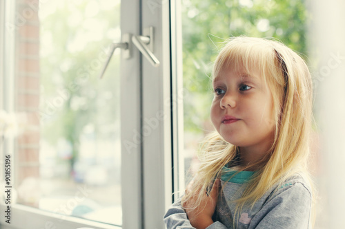 Portrait of 5 years old girl lsitting near the window