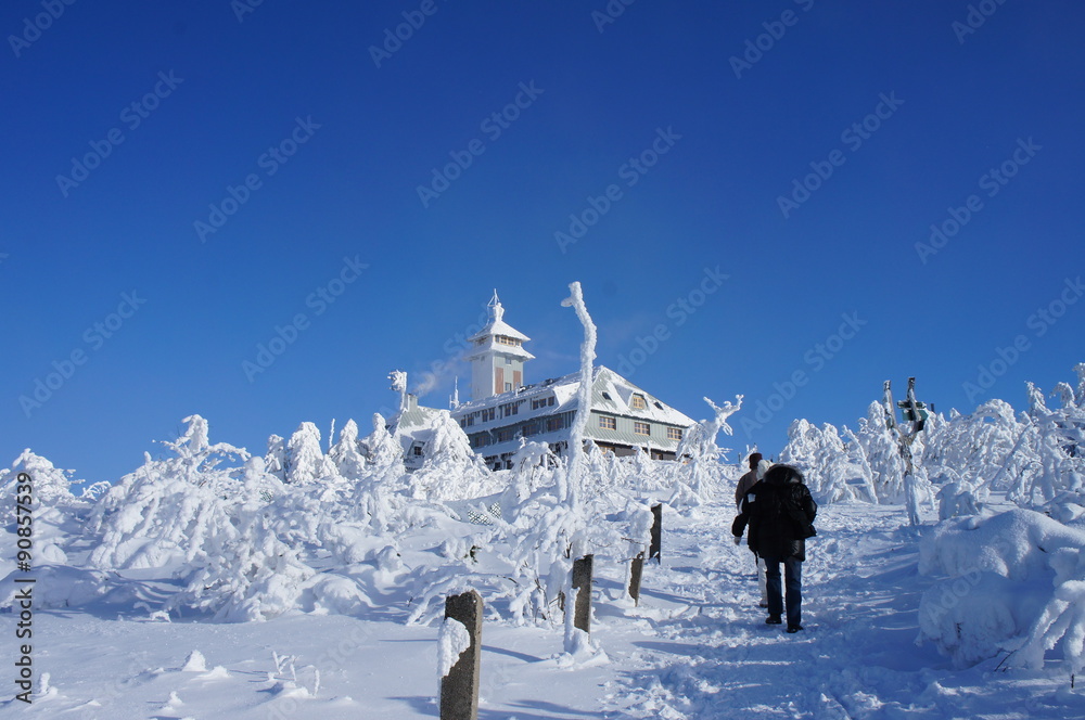 Wanderer auf dem Fichtelberg/Das Fichtelberghaus im Winter, traumhafte Kulisse auf dem Fichtelberg im Erzgebirge, dick verschneite Bäume und Büsche und wolkenloser HImmel