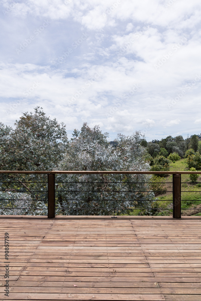 Large wood deck near house with spring landscape.