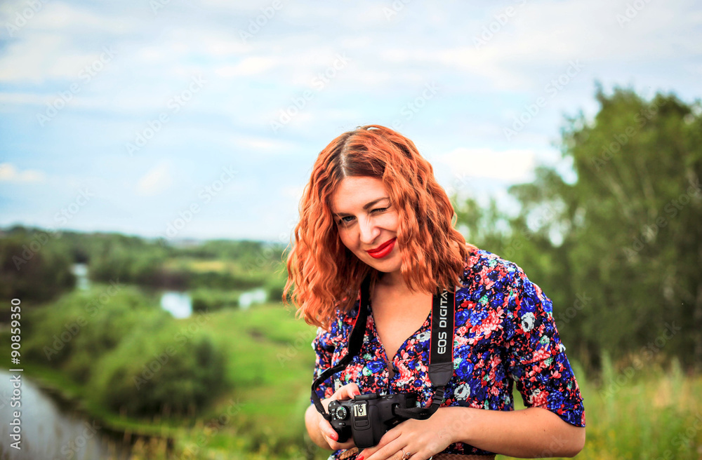 Fototapeta premium Portrait of pretty young red-haired woman with camera