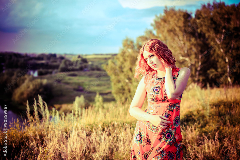 Young red-haired woman on the rock near river is fashionable Young red-haired woman on the rock near river is fashionable
