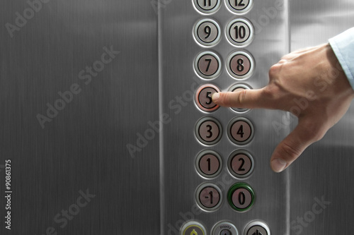 Forefinger pressing the fifth floor button in the elevator photo
