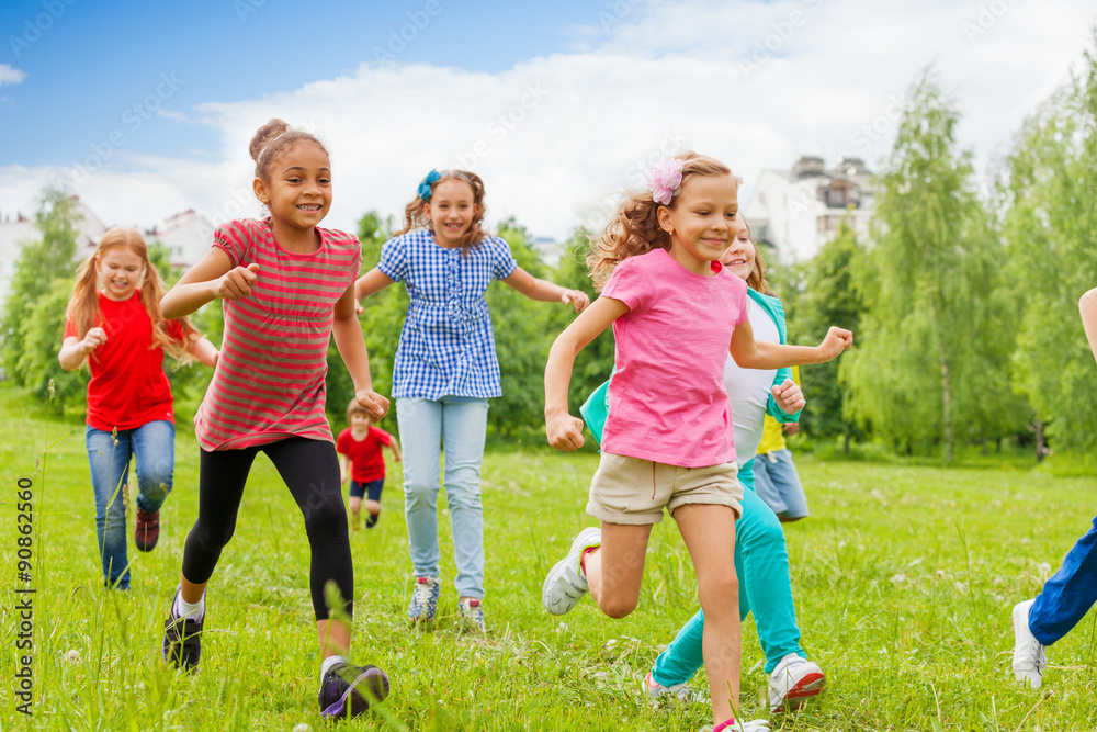Group of happy kids running through green field