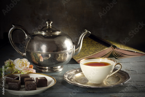 tea in a porcelain cup, old fashioned silver teapot, chocolate c