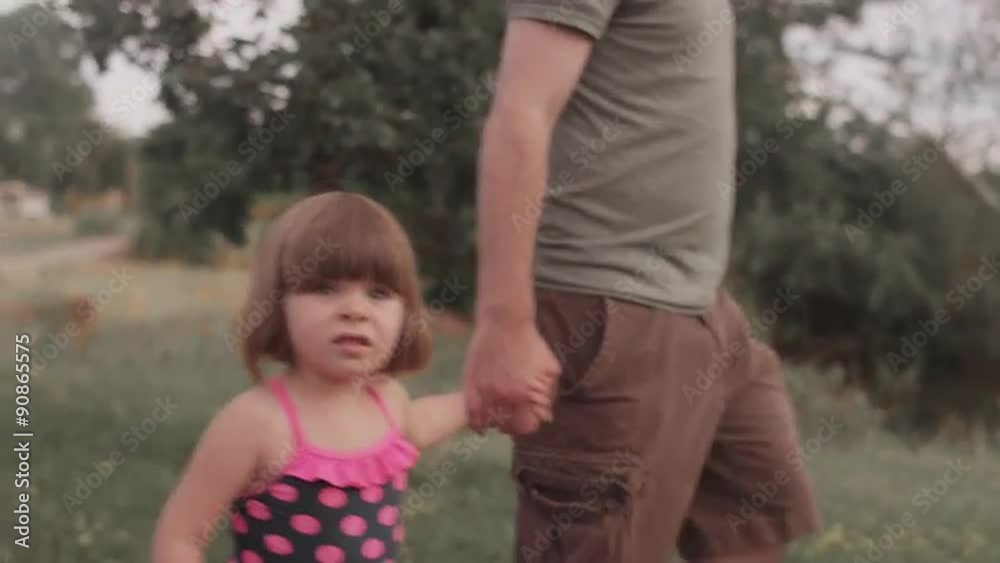 A little girl and her dad walk hand in hand down a park trail
A little girl and her dad walk hand in hand down a park trail