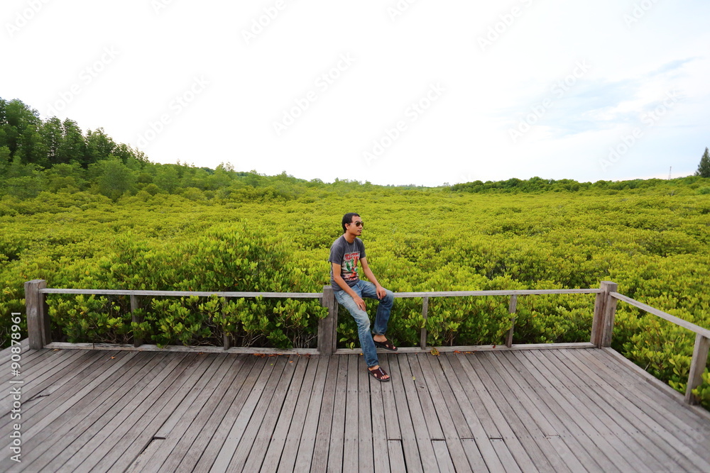 Man and walkway made from wood and mangrove field Man and walkway made from wood and mangrove field