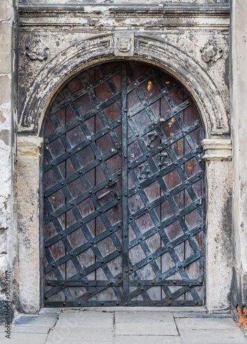 Old iron door reinforced with steel belts and rivets in decorative stone portal